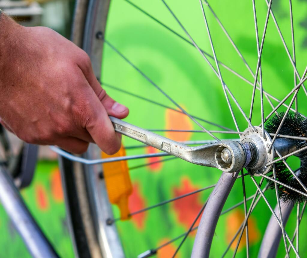 Close-up of a mechanic's hands truing a bicycle wheel with a wrench